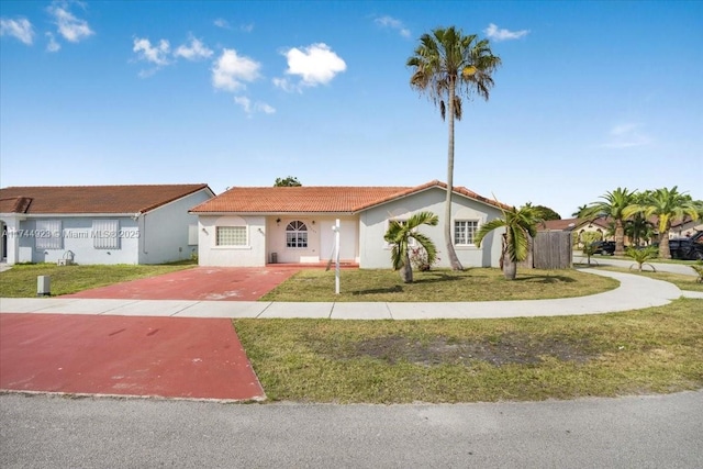 view of front of home with a front lawn, a tile roof, driveway, and stucco siding