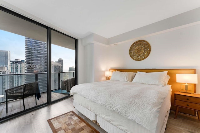 bedroom with floor to ceiling windows, access to outside, and light hardwood / wood-style floors