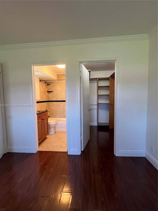 corridor featuring dark wood-type flooring and ornamental molding