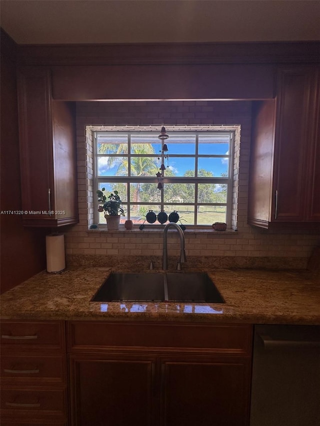 kitchen featuring tasteful backsplash, dishwasher, sink, and stone counters