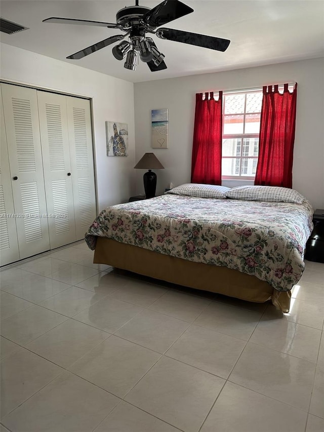 bedroom featuring light tile patterned floors, ceiling fan, and a closet