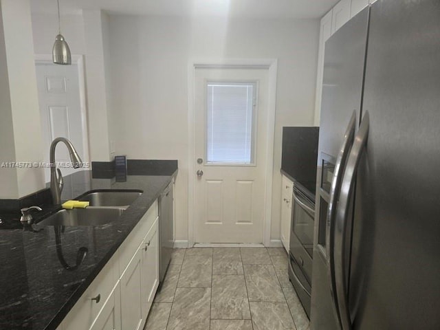 kitchen with pendant lighting, sink, white cabinetry, dark stone countertops, and stainless steel appliances