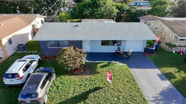 view of front of home featuring central AC, aphalt driveway, an attached garage, and a front yard