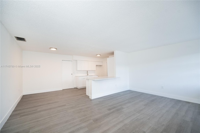 spare room with a textured ceiling, baseboards, and wood finished floors