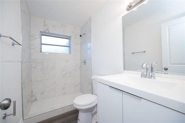 bathroom with toilet, a marble finish shower, and vanity