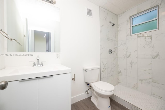 full bathroom with a marble finish shower, visible vents, toilet, wood finished floors, and vanity