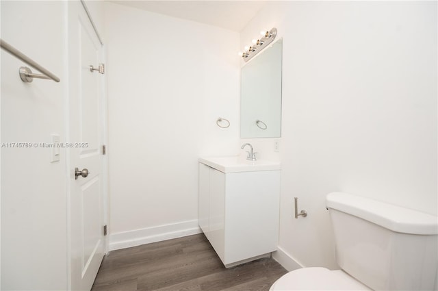 bathroom with baseboards, vanity, toilet, and wood finished floors