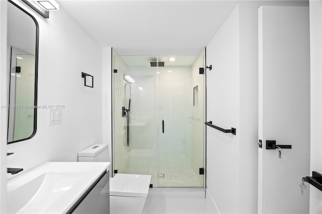 bathroom featuring vanity, a shower with shower door, and toilet