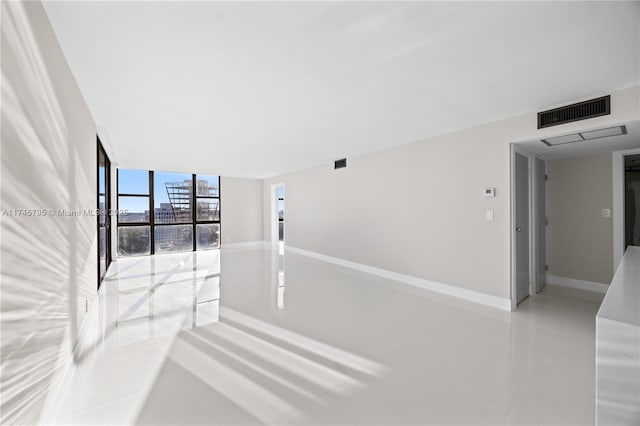 tiled spare room with a wall of windows