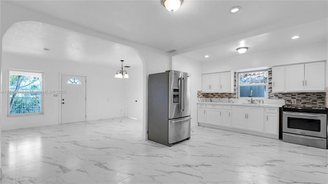 kitchen with backsplash, decorative light fixtures, white cabinets, and appliances with stainless steel finishes