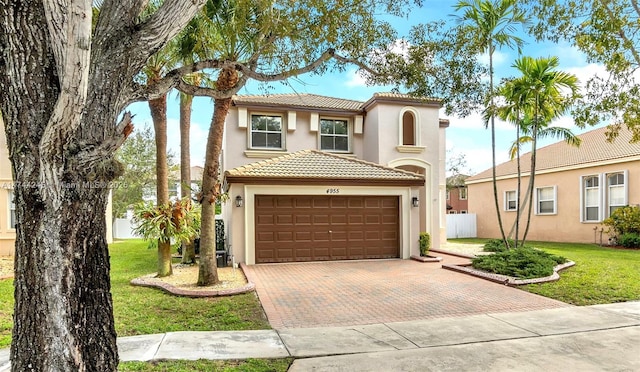 mediterranean / spanish home with a garage and a front lawn