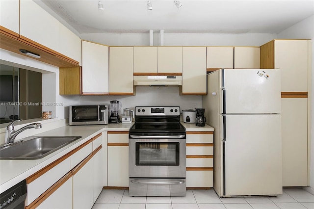 kitchen with light tile patterned flooring, appliances with stainless steel finishes, sink, and white cabinets