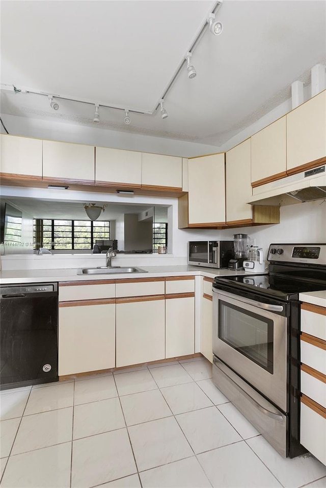 kitchen with sink, light tile patterned floors, stainless steel appliances, kitchen peninsula, and cream cabinetry