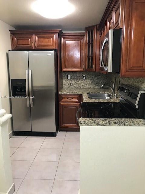 kitchen featuring sink, backsplash, light tile patterned floors, stainless steel appliances, and light stone countertops