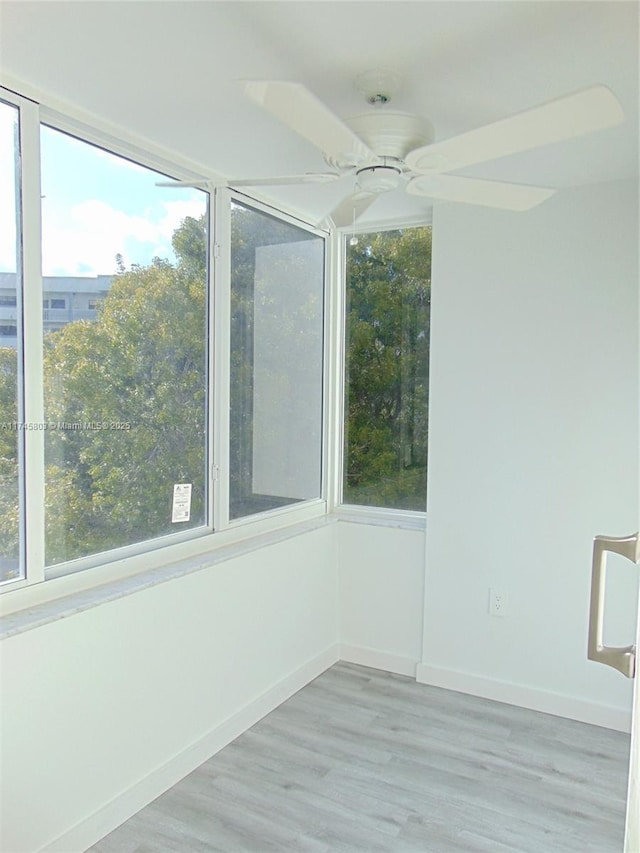 spare room with light wood-type flooring, a wealth of natural light, and ceiling fan