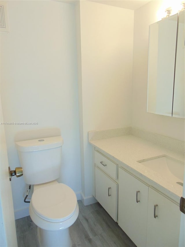 bathroom featuring vanity, wood-type flooring, and toilet