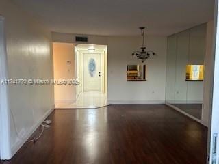 spare room featuring dark hardwood / wood-style floors and a chandelier