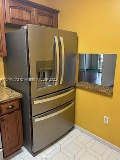 kitchen with stainless steel refrigerator with ice dispenser and stone countertops