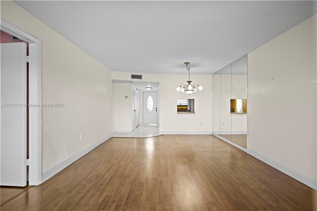 2811 N Pine Island Rd Unit 302, Sunrise, FL 33322 - unfurnished living room featuring visible vents, baseboards, wood finished floors, and a chandelier