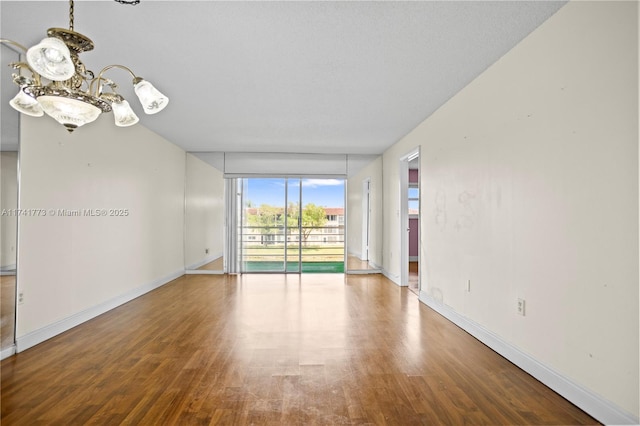 2811 N Pine Island Rd Unit 302, Sunrise, FL 33322 - empty room featuring baseboards, a wall of windows, wood finished floors, and an inviting chandelier