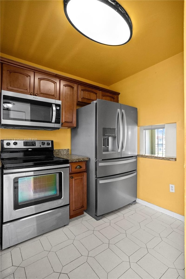 2811 N Pine Island Rd Unit 302, Sunrise, FL 33322 - kitchen with brown cabinets, baseboards, appliances with stainless steel finishes, and vaulted ceiling