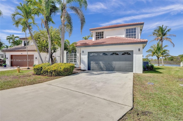 mediterranean / spanish house with a garage, driveway, stucco siding, a tile roof, and a front yard