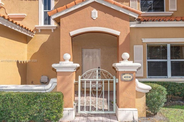 view of exterior entry featuring a tiled roof and stucco siding