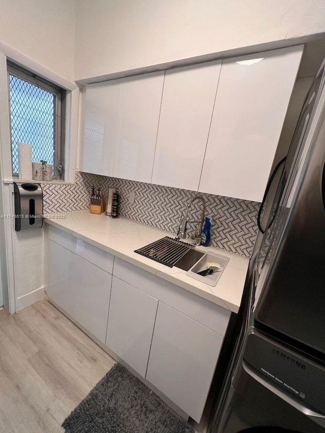 kitchen featuring white cabinetry, sink, light wood-type flooring, and decorative backsplash