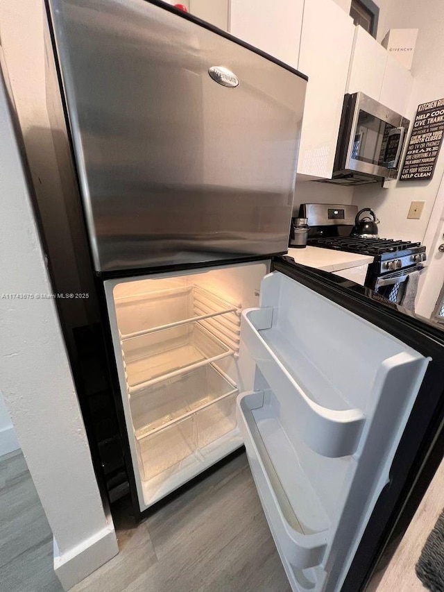 kitchen featuring appliances with stainless steel finishes, wood-type flooring, and white cabinets