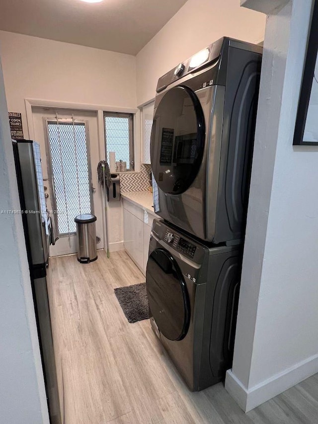 laundry room with stacked washer / drying machine and light hardwood / wood-style floors