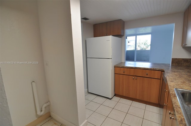 kitchen with sink, light tile patterned flooring, and white refrigerator