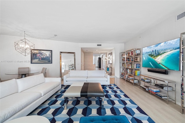 living room with a notable chandelier and light hardwood / wood-style floors