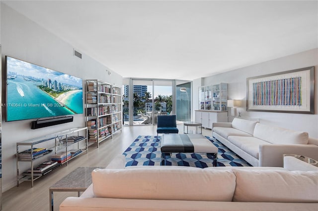 living room with a wall of windows and light wood-type flooring