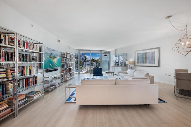 living room featuring expansive windows, a chandelier, and light wood-type flooring