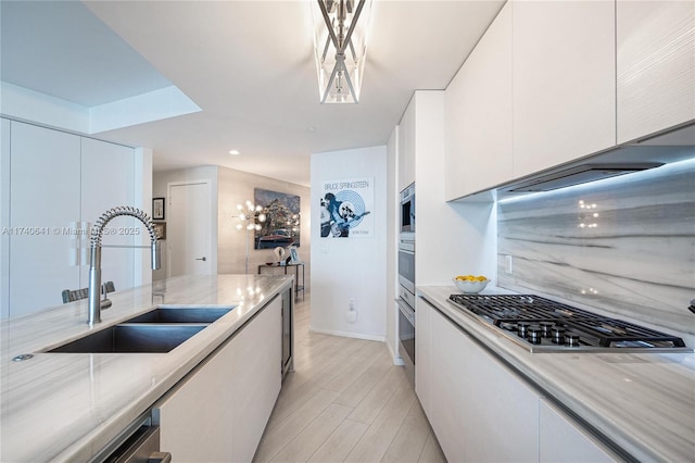 kitchen with white cabinetry, appliances with stainless steel finishes, sink, and light wood-type flooring