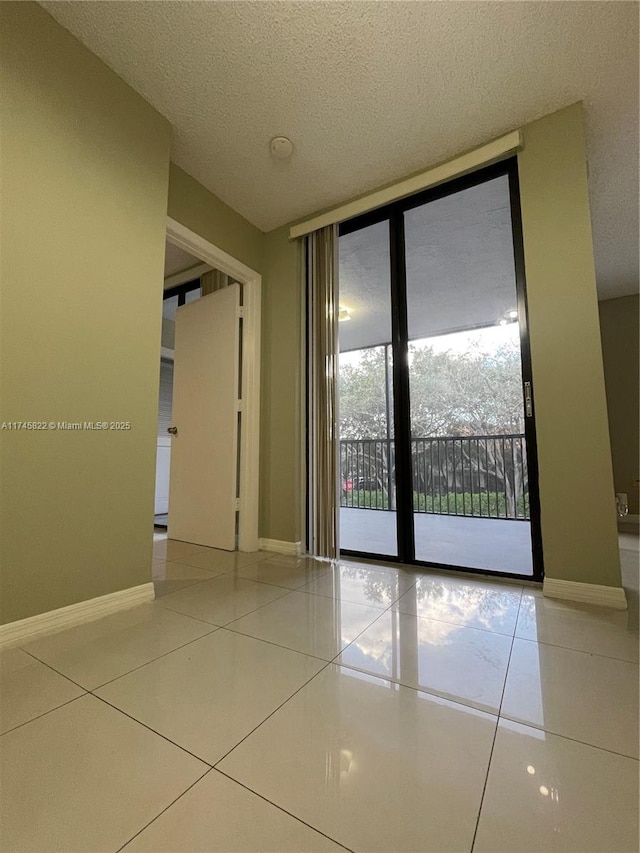 empty room featuring tile patterned floors, expansive windows, and a textured ceiling