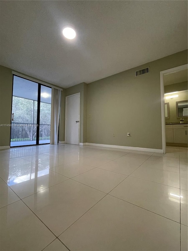 tiled empty room with expansive windows and a textured ceiling