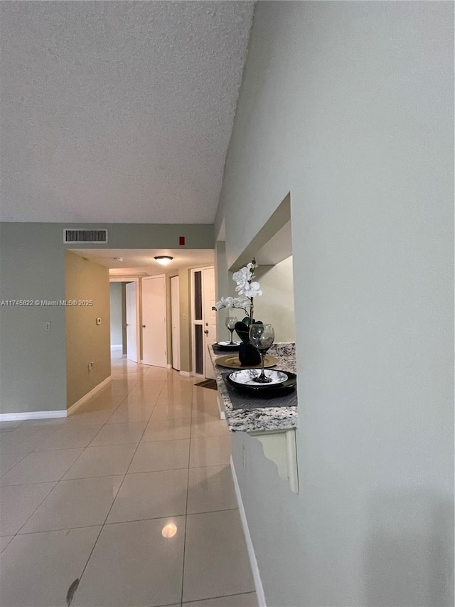 corridor featuring light tile patterned flooring and a textured ceiling