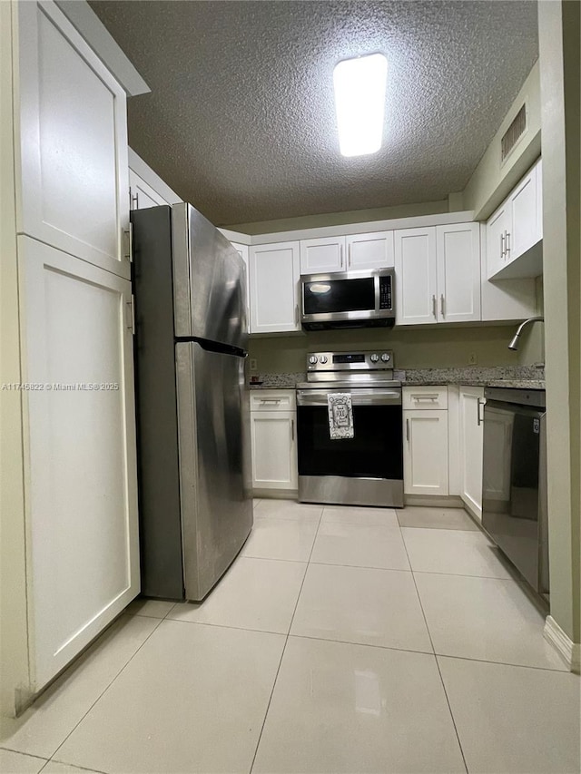 kitchen with white cabinetry, light tile patterned floors, a textured ceiling, and appliances with stainless steel finishes