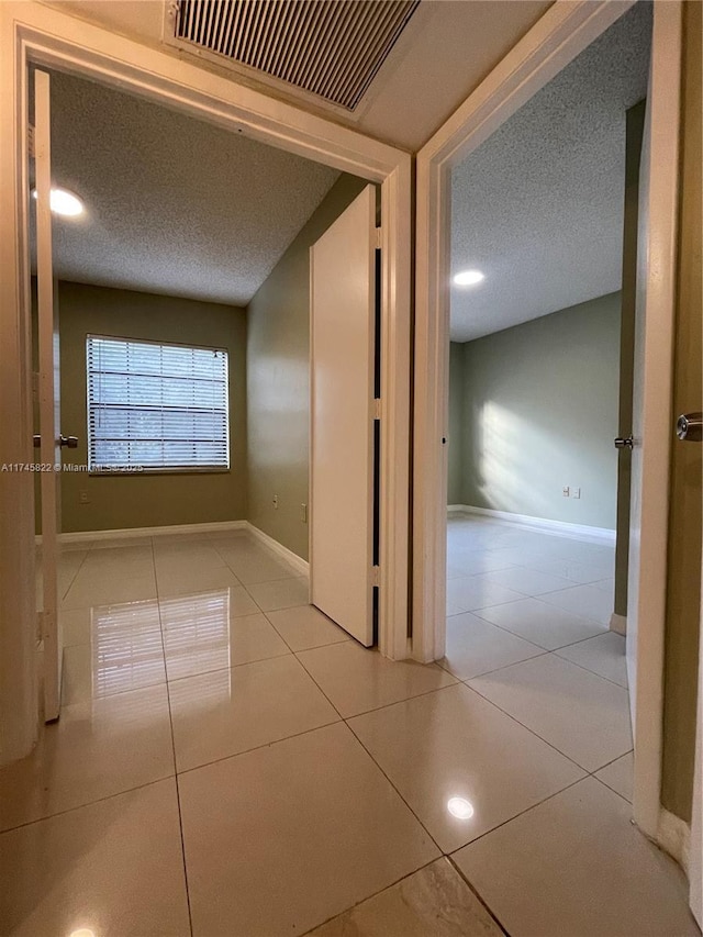 hall with light tile patterned floors and a textured ceiling