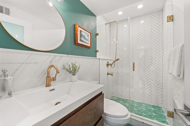 bathroom with vanity, toilet, a shower with door, and tile walls