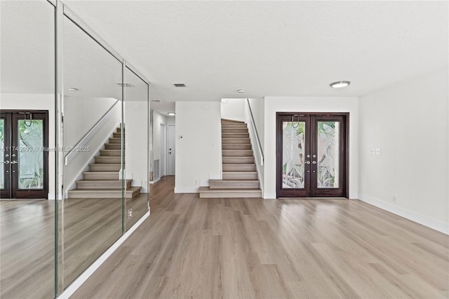 foyer with french doors, a healthy amount of sunlight, a textured ceiling, and light wood-type flooring