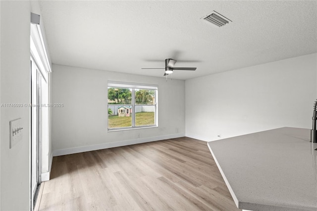 unfurnished bedroom featuring ceiling fan, a textured ceiling, and light wood-type flooring