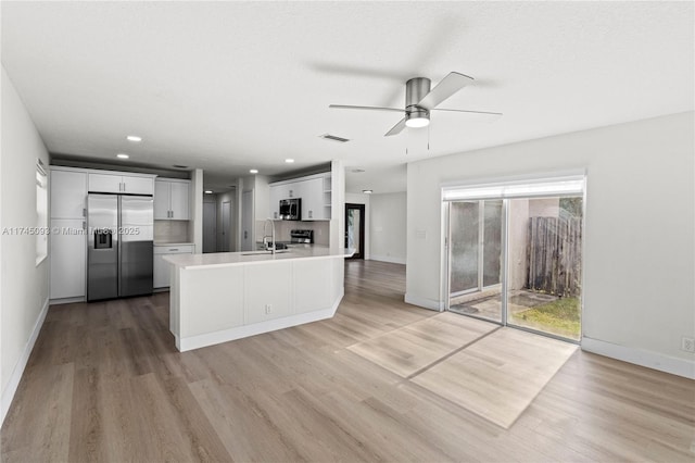 kitchen with appliances with stainless steel finishes, white cabinetry, sink, kitchen peninsula, and light wood-type flooring