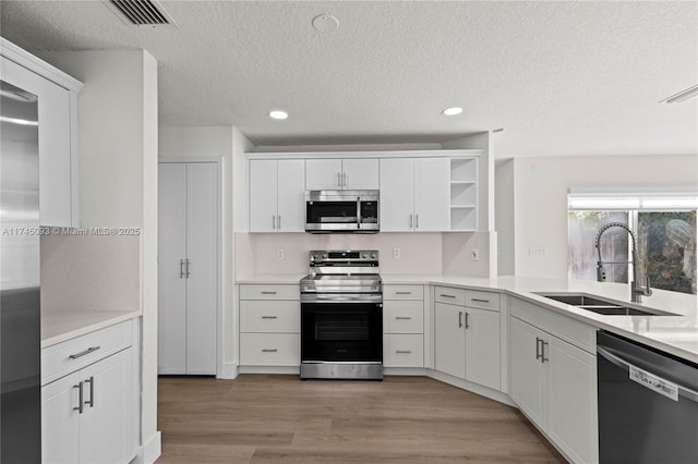 17356 SW 21st St, Miramar, FL 33029 - kitchen featuring appliances with stainless steel finishes, a sink, open shelves, white cabinetry, and a textured ceiling