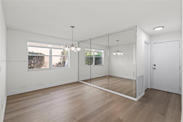 unfurnished bedroom featuring hardwood / wood-style flooring, multiple closets, and a chandelier