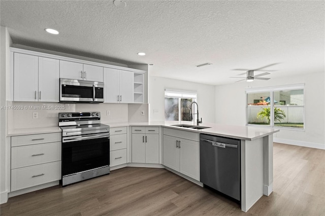 17356 SW 21st St, Miramar, FL 33029 - kitchen featuring appliances with stainless steel finishes, a peninsula, open shelves, light wood finished floors, and a textured ceiling