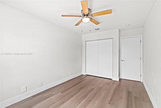 unfurnished bedroom featuring ceiling fan, light wood-type flooring, and a closet