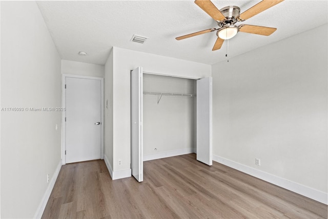 unfurnished bedroom featuring ceiling fan, light hardwood / wood-style flooring, a textured ceiling, and a closet