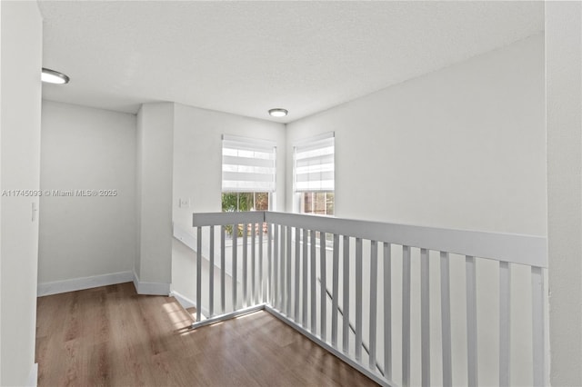 hallway with hardwood / wood-style flooring and a textured ceiling